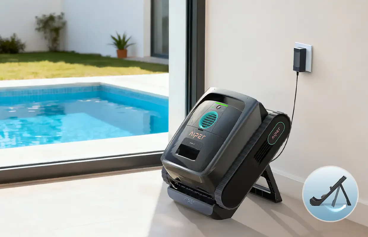 AIPER Scuba V3 leaning back on its fold-out charging stand beside a pool, with the wall plug cable running to the stand
