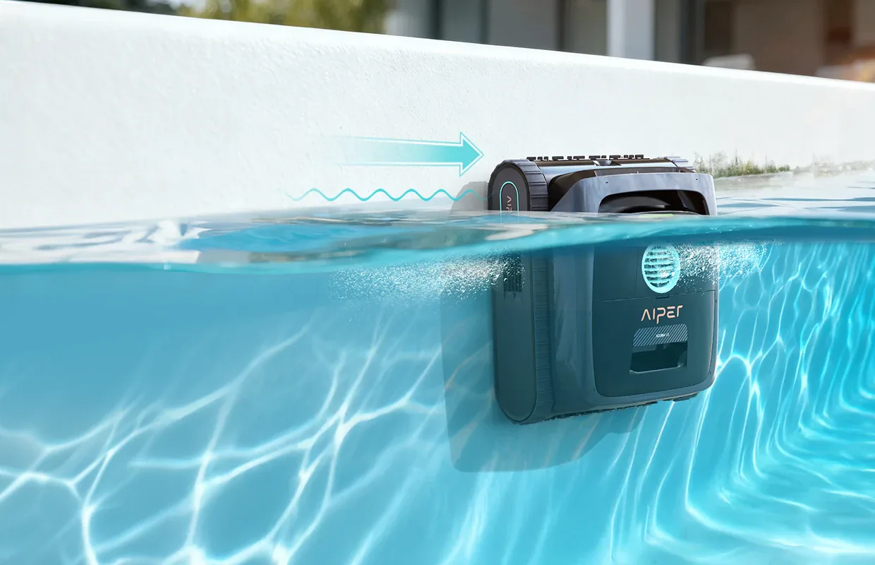 AIPER Scuba V3 at the pool waterline against the wall, top edge above the water, with an arrow drawn along the wall